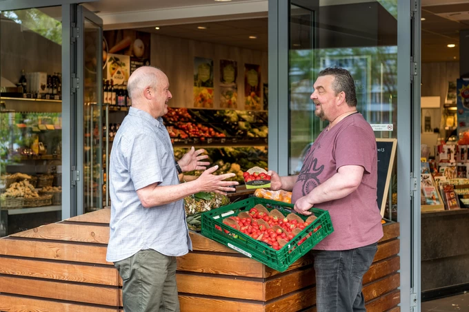 Leerwerkburo-reintegratie-twee-mannen-pratend-groentenwinkel-tomaten