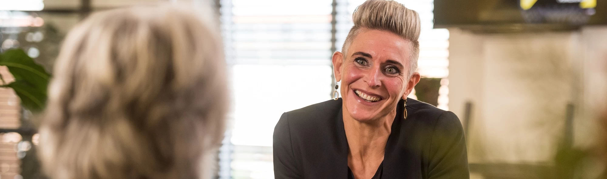 "leerwerkburo reintegratie lachende vrouw met kort haar en zwart jasje"