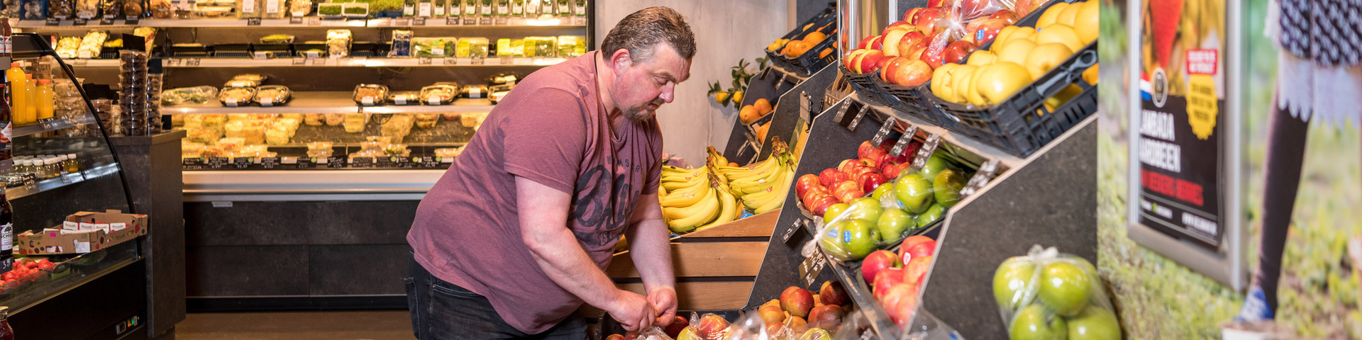 "leerwerkburo reintegratie man in rood shirt aan het werk in fruitwinkel"