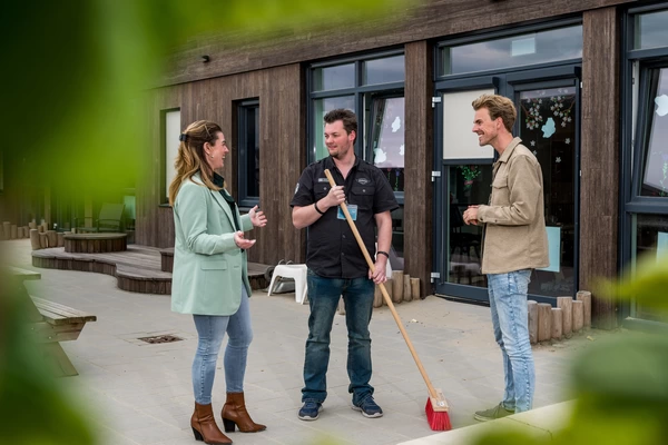 "leerwerkburo reintegratie dame en twee mannen op schoolplein in gesprek met elkaar"