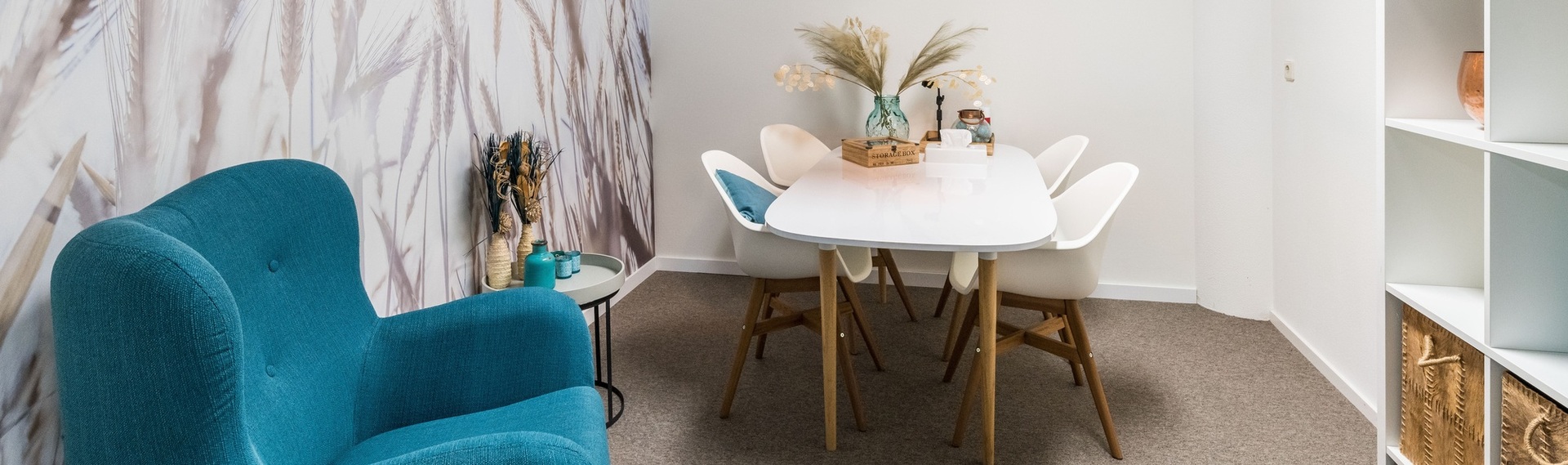 "leerwerkburo reintegratie coachruimte met tafel, stoelen en blauwe fauteuil"
