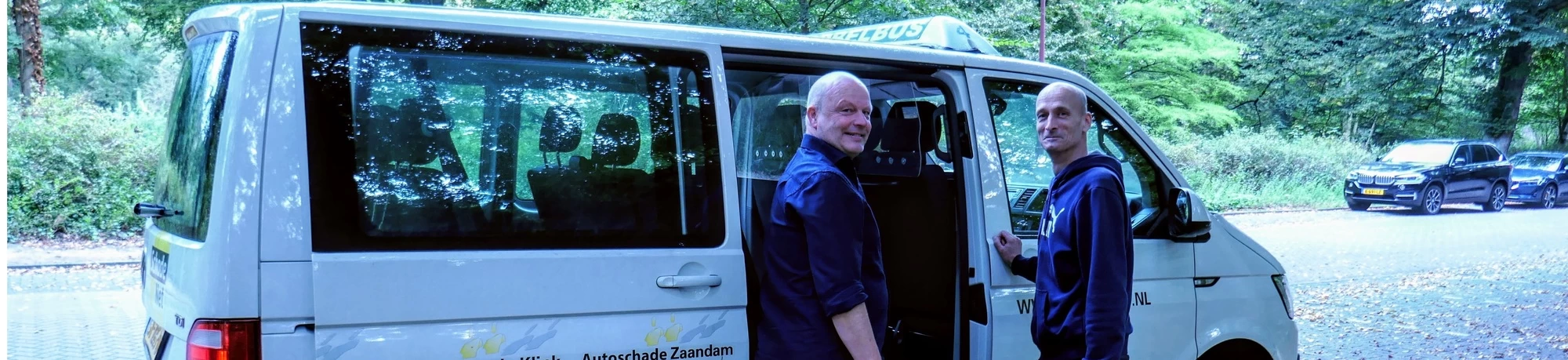 "leerwerkburo reintegratie twee mannen praten voor witte autobus"