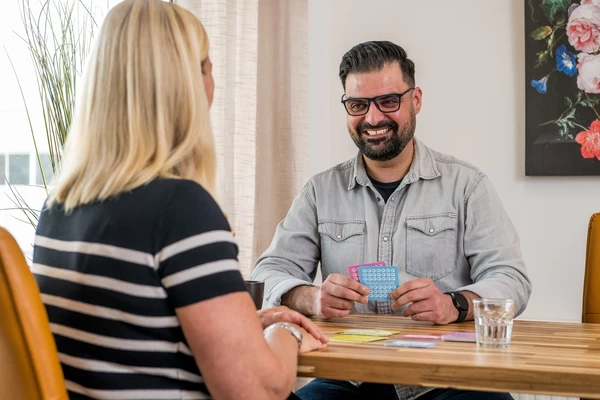 "leerwerkburo reintegratie lachende man met bril en baard aan tafel met vrouw"