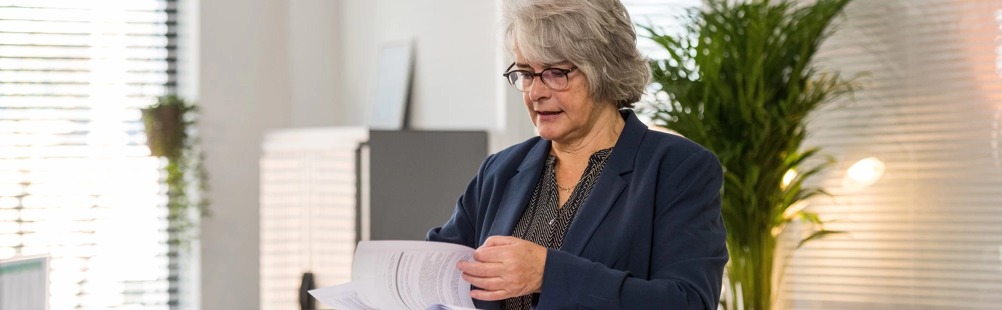 "leerwerkburo reintegratie vrouw met grijs haar en bril en blauw jasje"