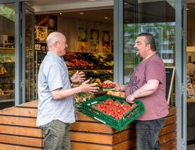 Leerwerkburo-reintegratie-twee-mannen-pratend-groentenwinkel-tomaten