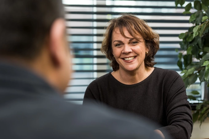 leerwerkburo-reintegratie-lachende-mevrouw-met zwarte-trui-plant-luxaflex-meneer