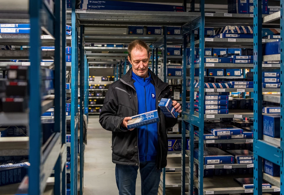 Nico aan het werk om voor klanten de bestelde auto-onderdelen te verzamelen