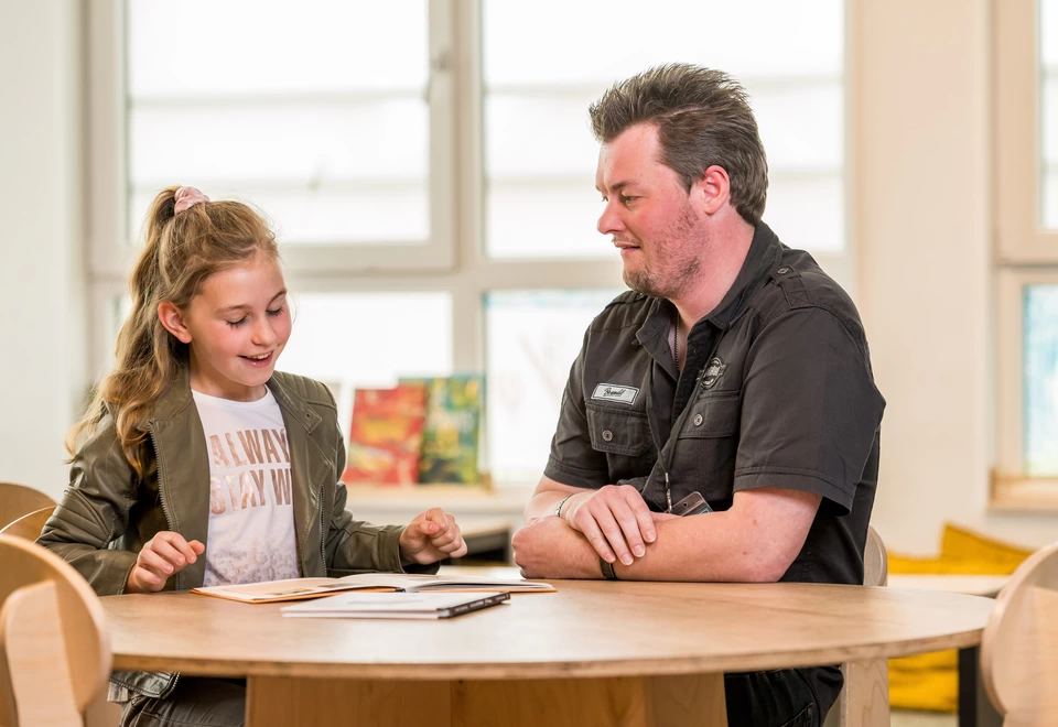 Bram helpt een leerling op school bij het extra oefenen van lezen